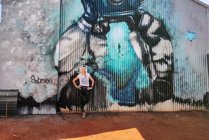 A woman in front of a colourful mural