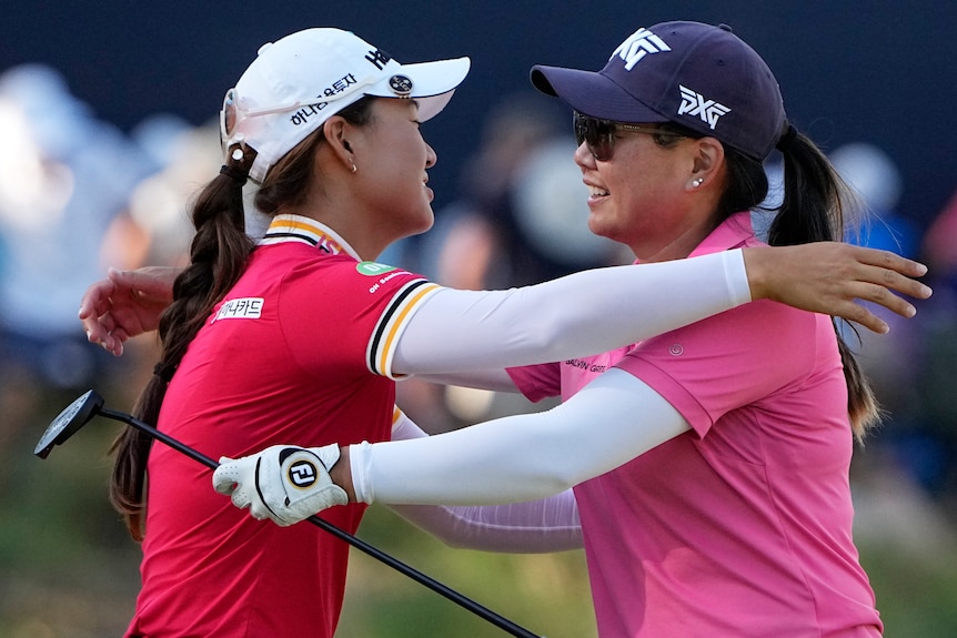 Australian golfer Minjee Lee puts her arms around putter-holding Mina Harigae.