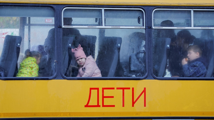 Chilren sitting on train with Russian text on the carriage