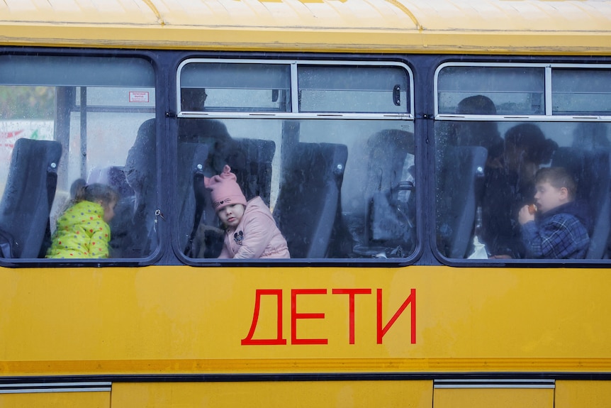 Chilren sitting on train with Russian text on the carriage