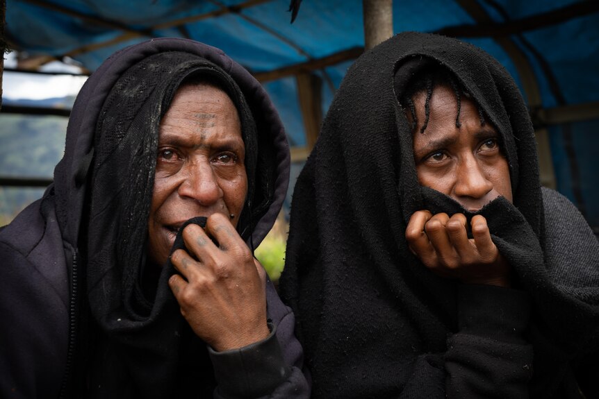 two women wrapped in blankets looking worried or sad