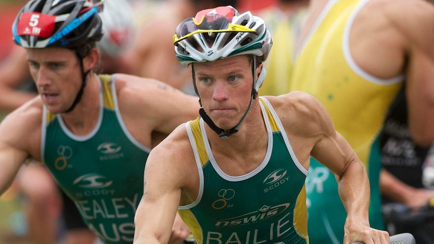 A man in a green lycra suit standing next to a racing bicycle.