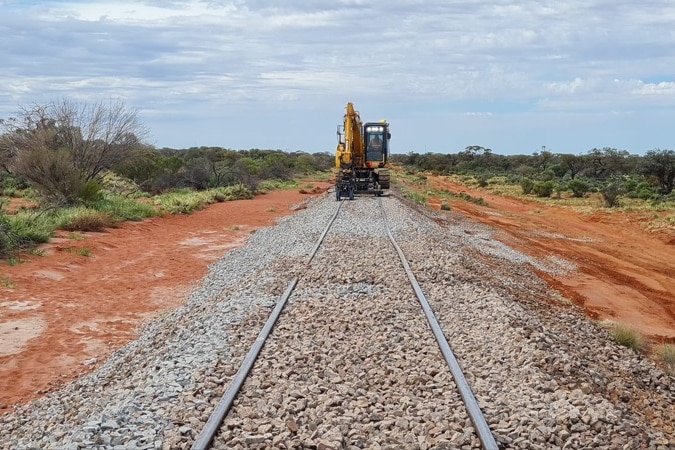 An excavator on a railway track full of ballast