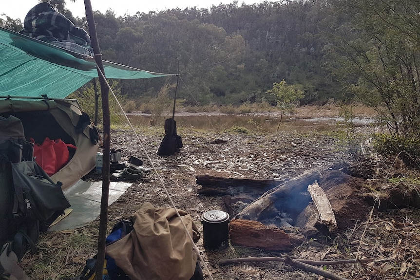 A camp site in Licola. Billy and swag in foreground, with river in the background