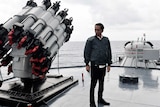 Indonesian President Joko Widodo looks at a weapon on board a warship.