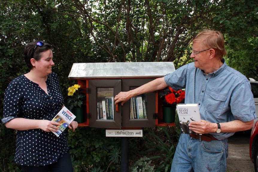 Sarah Steed, ACT Libraries' senior manager of content and engagement, with John Lovering and the Free Little Library he built outside his home in Curtin, ACT.