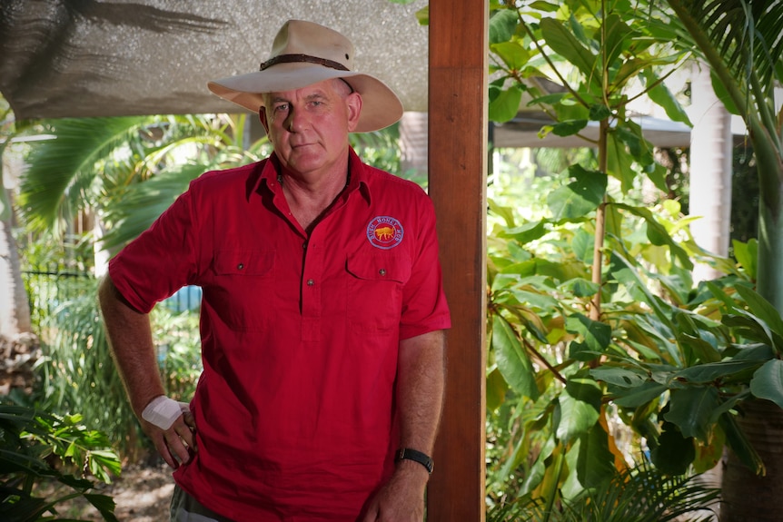 Alan Gray leans against a wooden pole on his veranda outside. He wears an akubra.