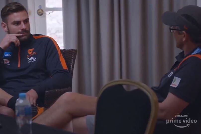 Stephen Coniglio holds his hand to his mouth while listening to Leon Cameron speak
