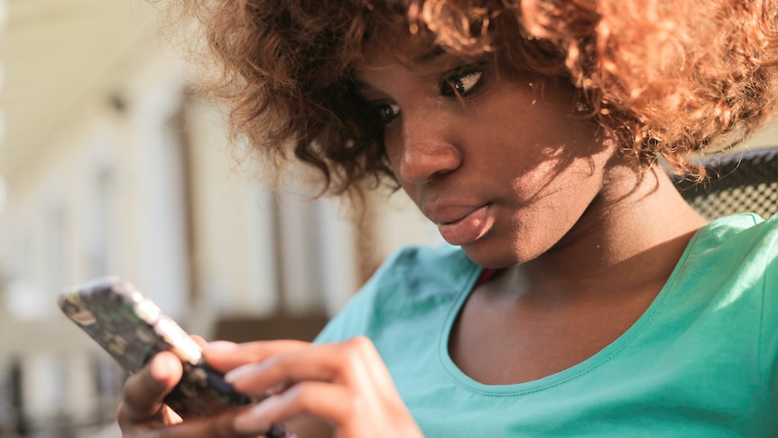 A woman looks at a mobile phone screen. For a story about people's family getting involved in work disputes. 