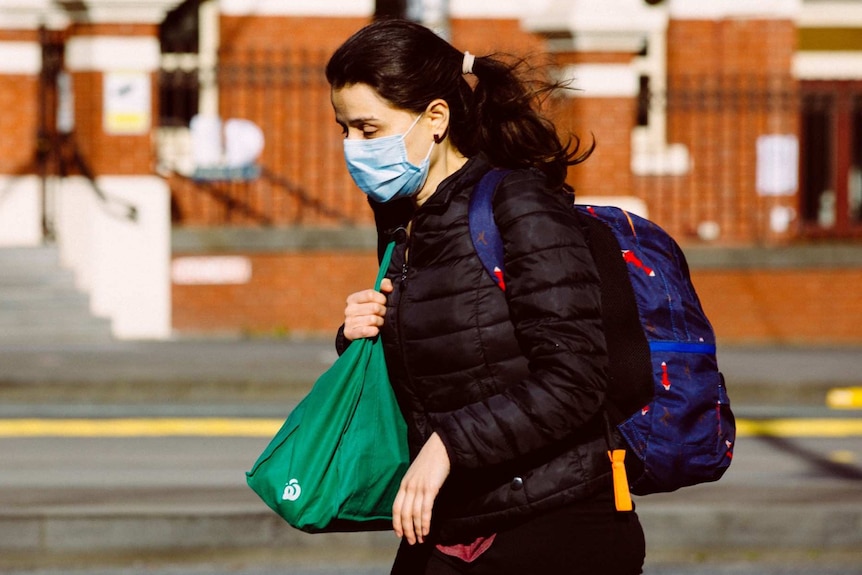 A woman wearing a face mask walks on a street in Melbourne.