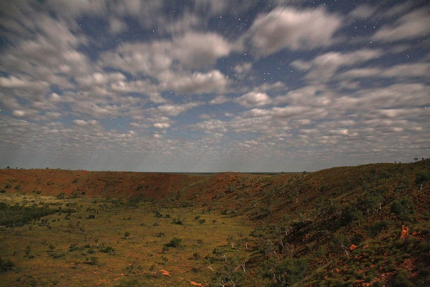 A night-time view of Wolfe Creek Crater with stars visible.