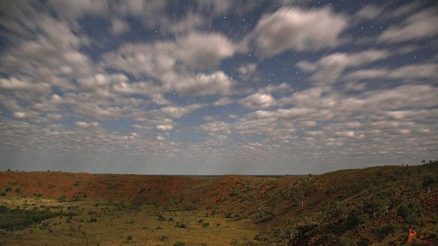A night-time view of Wolfe Creek Crater with stars visible.