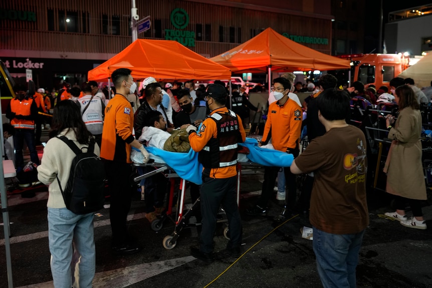 Rescue workers carry injured people at the street near the scene in Seoul.