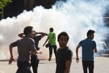 Protesters run from tear gas fired by riot police.