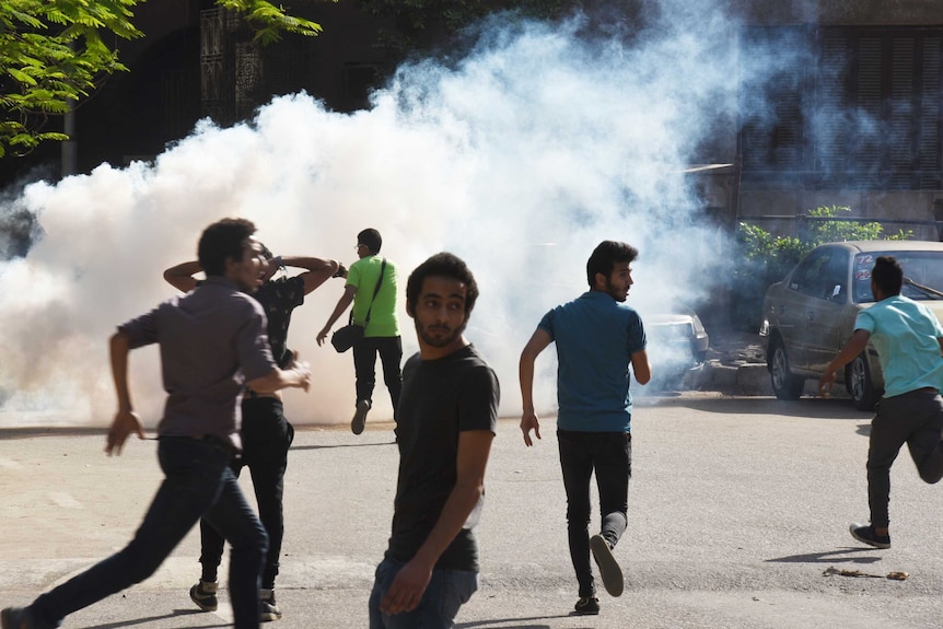 Protesters run from tear gas fired by riot police.