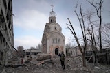 A Ukrainian serviceman takes a photograph of a damaged church after shelling.