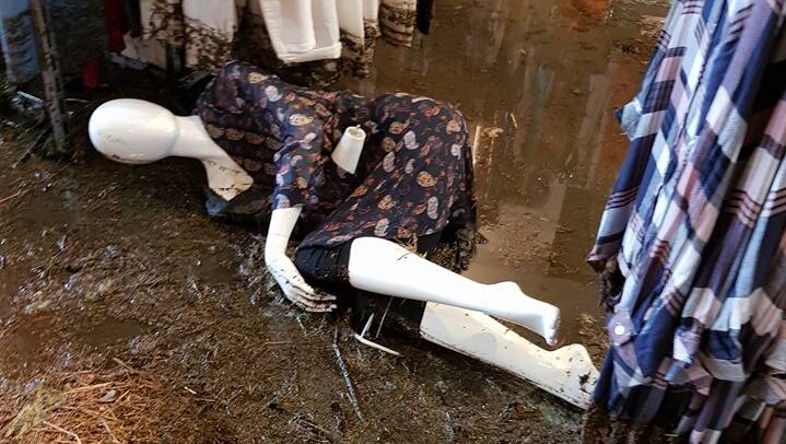A shop mannequin lies amidst a shop damaged by a flood.