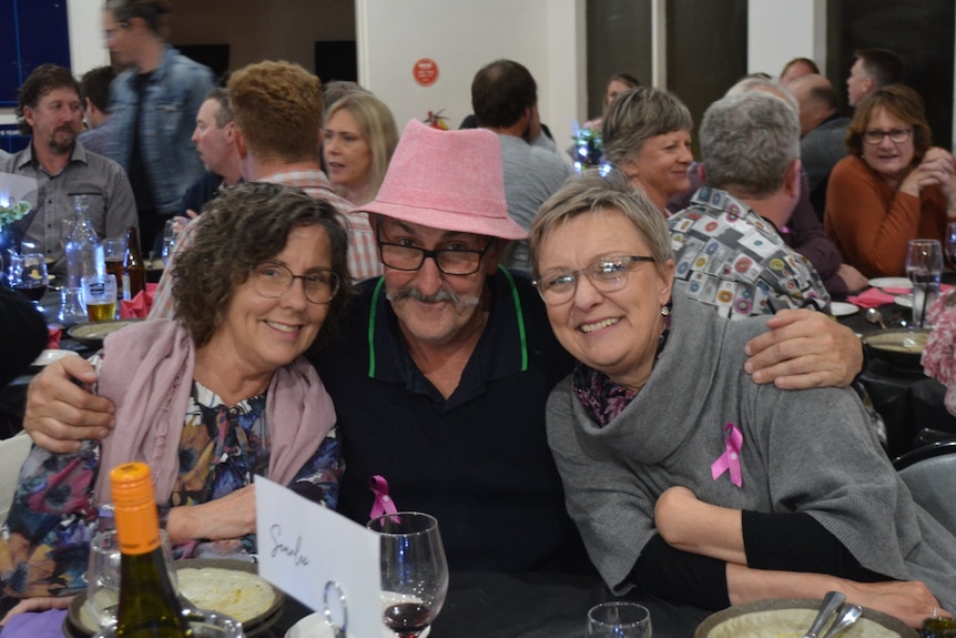 People smiling at the camera, man wearing a pink hat