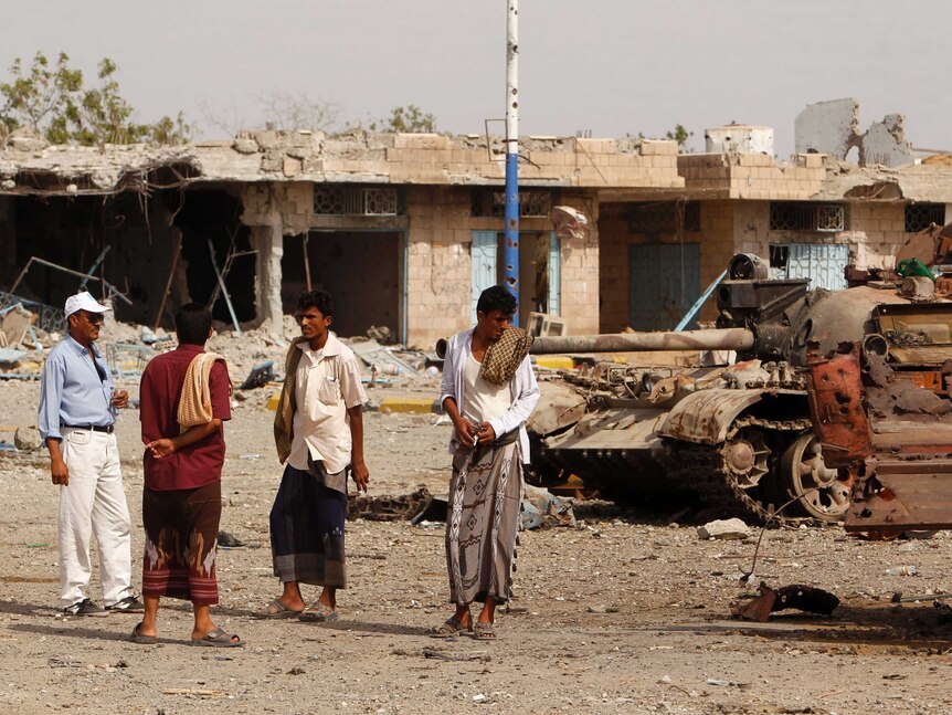 People chat on a street strewn with debris from fighting between the army and Al Qaeda-linked militants in Yemen.