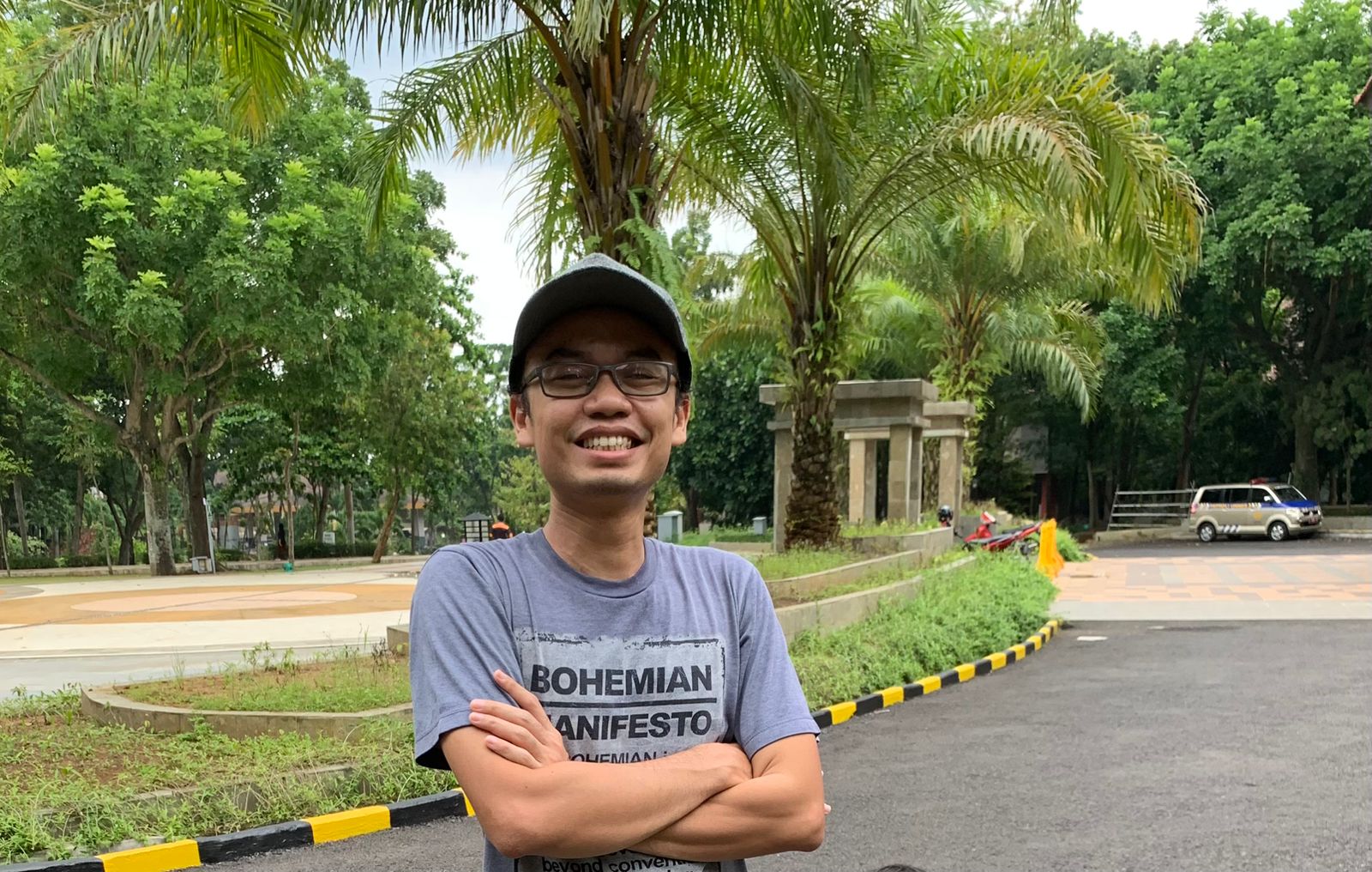 A man folding hands and smiling while facing the camera.