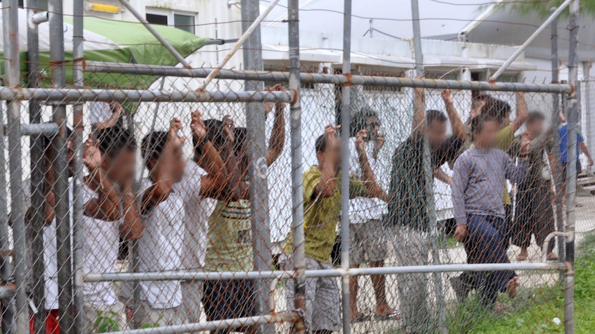 Asylum-seekers look through a fence at the Manus Island detention centre in Papua New Guinea