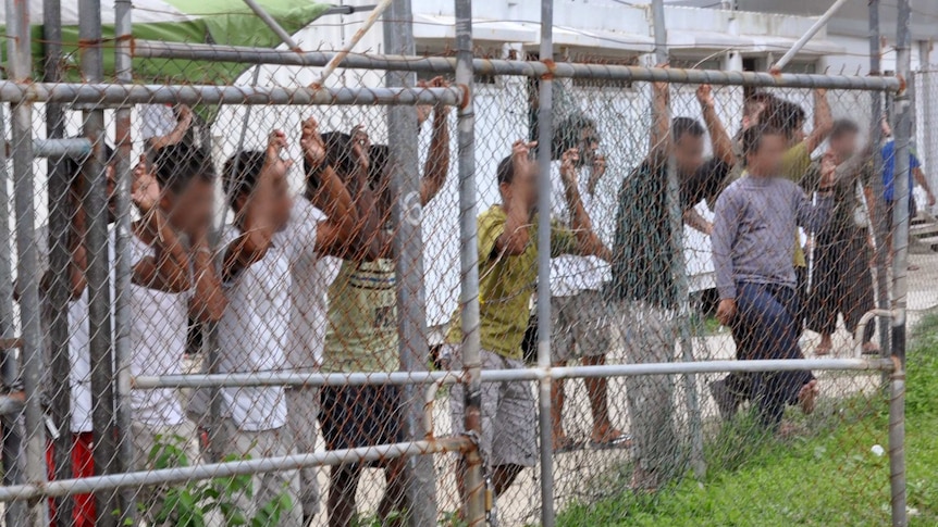 Asylum-seekers look through a fence at the Manus Island detention centre.