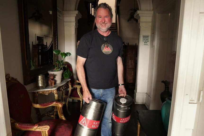 Man holding two kegs of beer.
