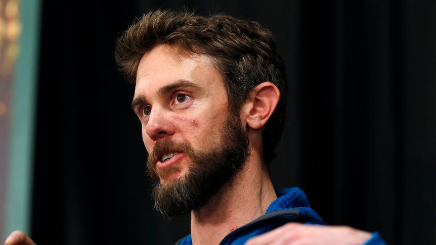 A man gestures with his hands as he answers at a press conference.