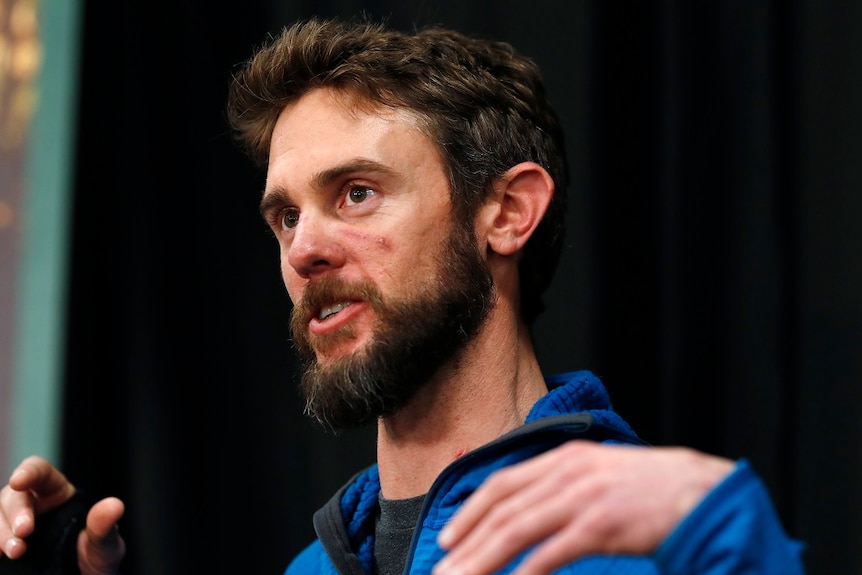 A man gestures with his hands as he answers at a press conference.