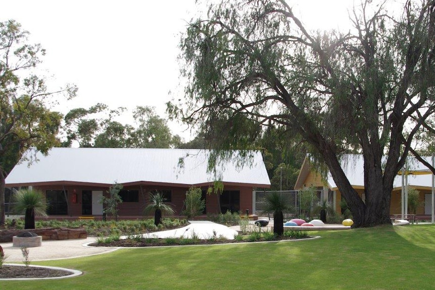 a view of Bennett Brook Disability Justice Centre with trees and lawn in the foreground.