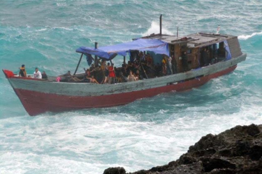 A boat carrying asylum seekers is bounced on rough surf.