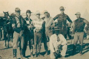 A black and white photo of male jockeys