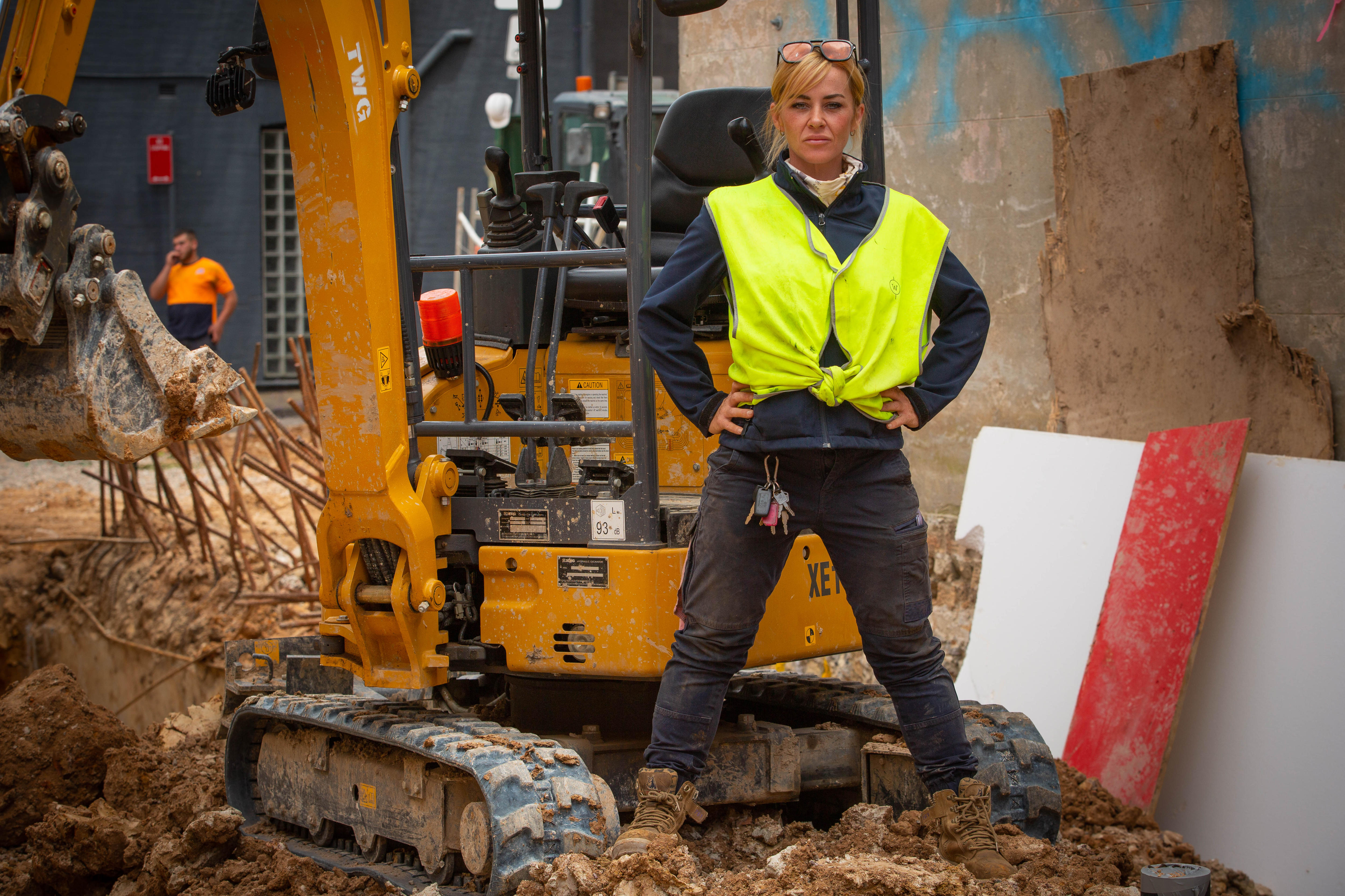 A young woman standing with her hands on her hips at a building worksite