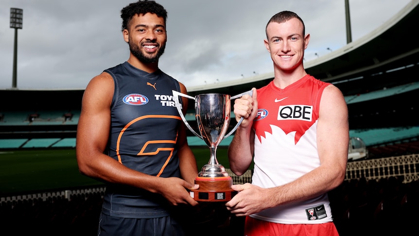 Connor Idun and Chad Warner pose for a photo while holding a trophy between them