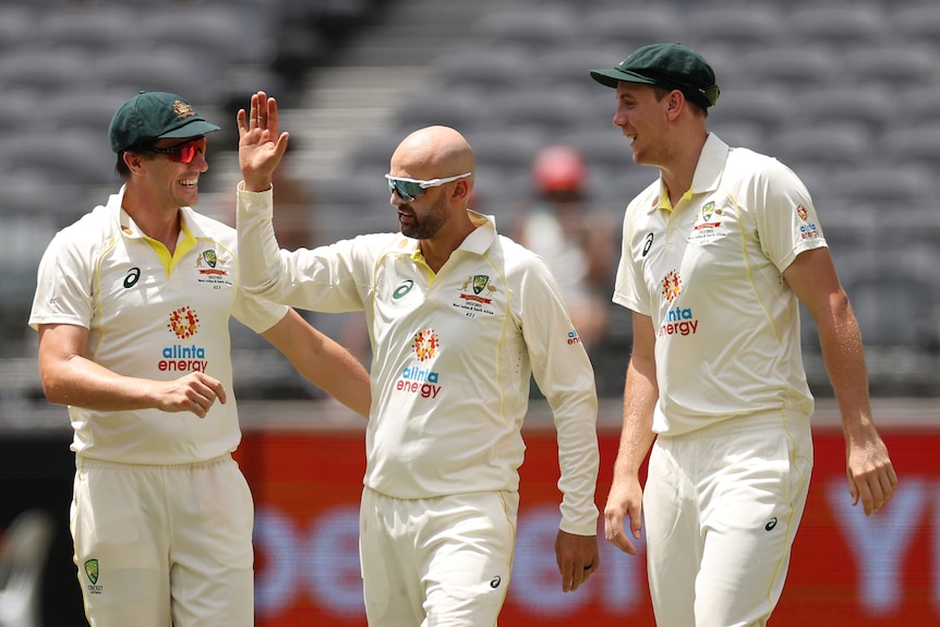 Pat Cummins and Cameron Green congratulate Australia bowler Nathan Lyon on a wicket in a Test against West Indies.