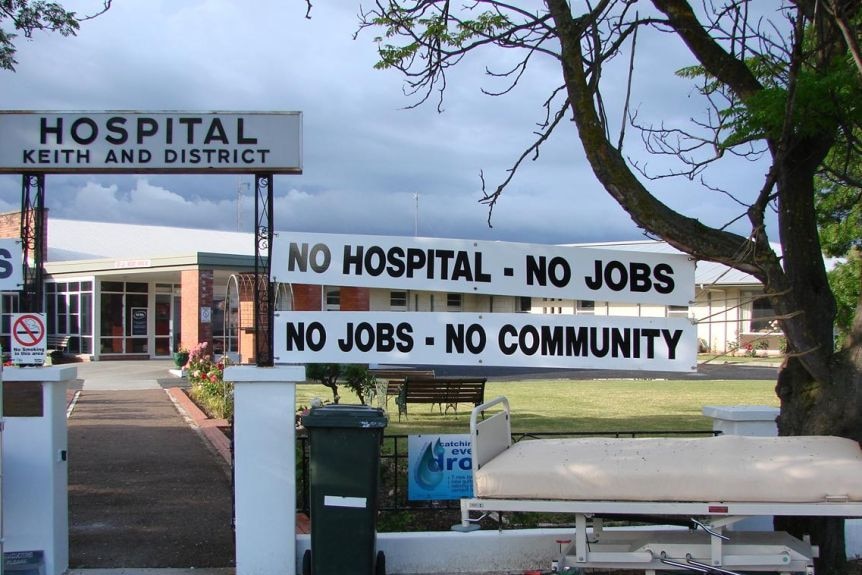Signs reading 'No hospital, no jobs. No jobs, no community' are pinned to the Keith and District Hospital entryway.