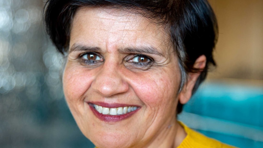 portrait of South Asian woman smiling with cropped black hair wearing yellow sweater