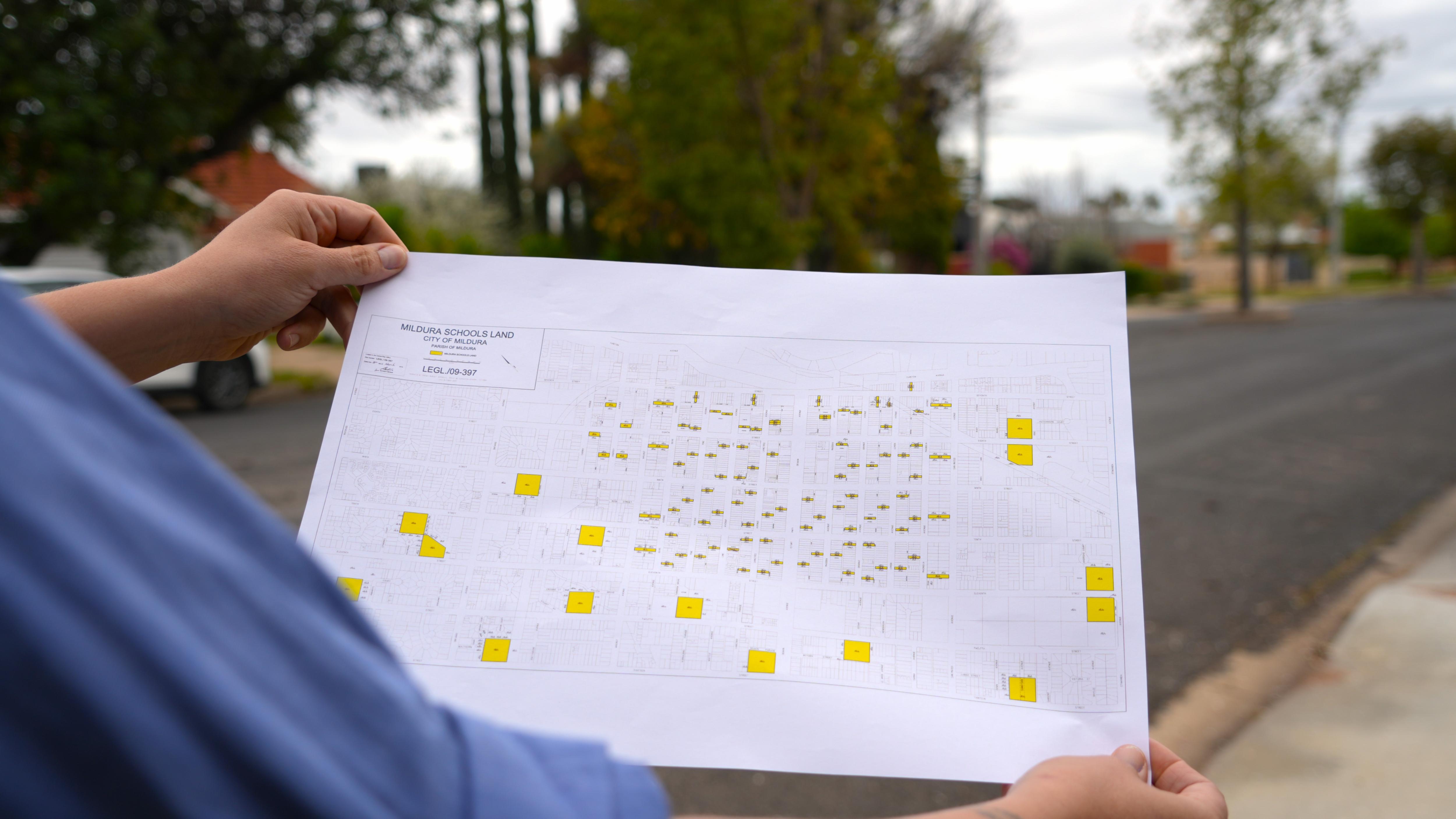 A woman holding a map with college lease land highlighted in yellow.