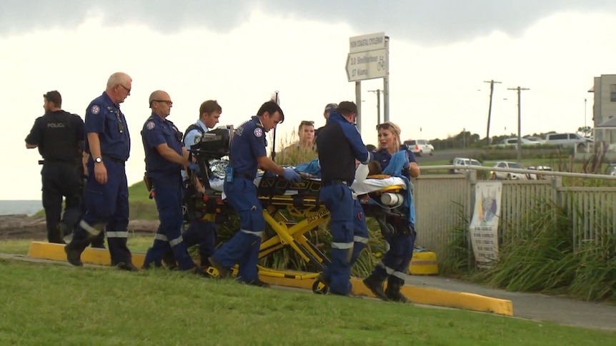 First responders assisting young boy on side of beach.