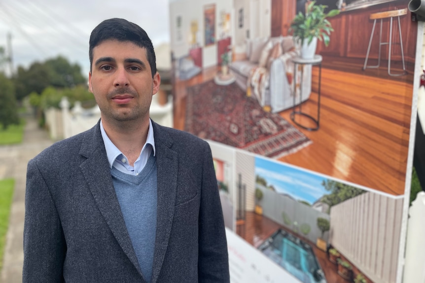 A young man in a blue suit standing outside a house