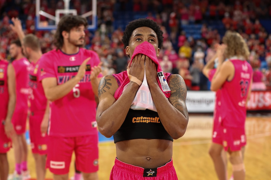 Bryce Cotton holds his jersey over his mouth and looks upwards in disappointement