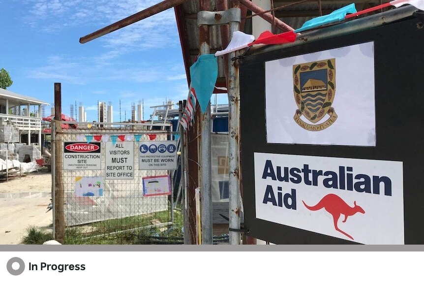 A sign that says "Australian Aid" with a red kangaroo on it outside of a construction site