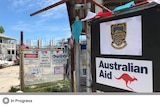 A sign that says "Australian Aid" with a red kangaroo on it outside of a construction site