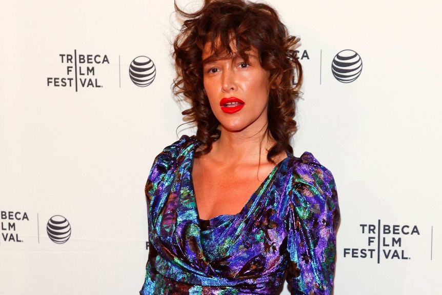 Actress Paz de la Huerta poses for photographers in front of a promotional backdrop.