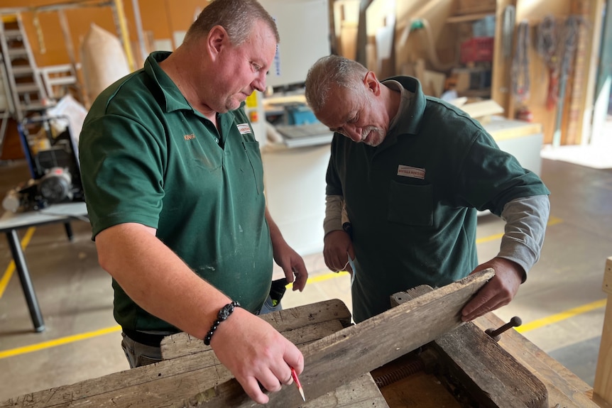 Two men working on converting an old work bench into a kitchen bench. 