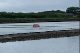 A red car in the middle of a river.