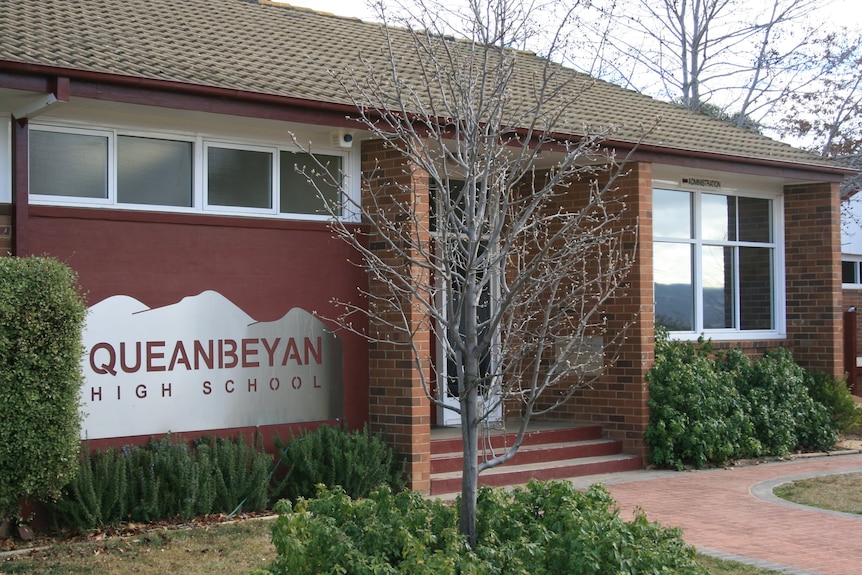 A red school with a sign reading 'Queanbeyan High School'.