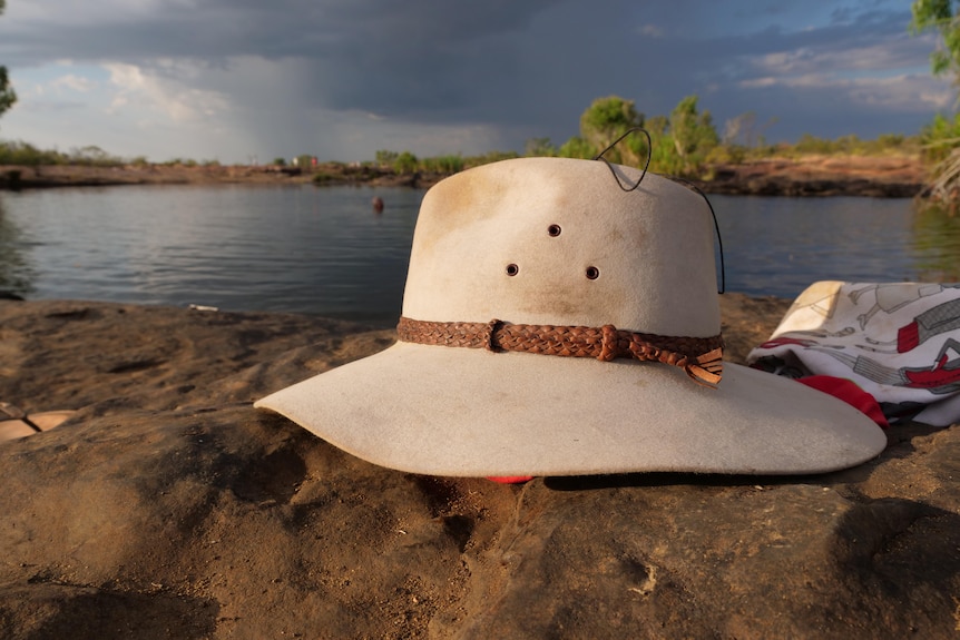 hat on ground with waterhole in the background