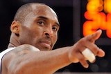 Kobe Bryant points back towards the camera, looking over his shoulder wearing a white singlet