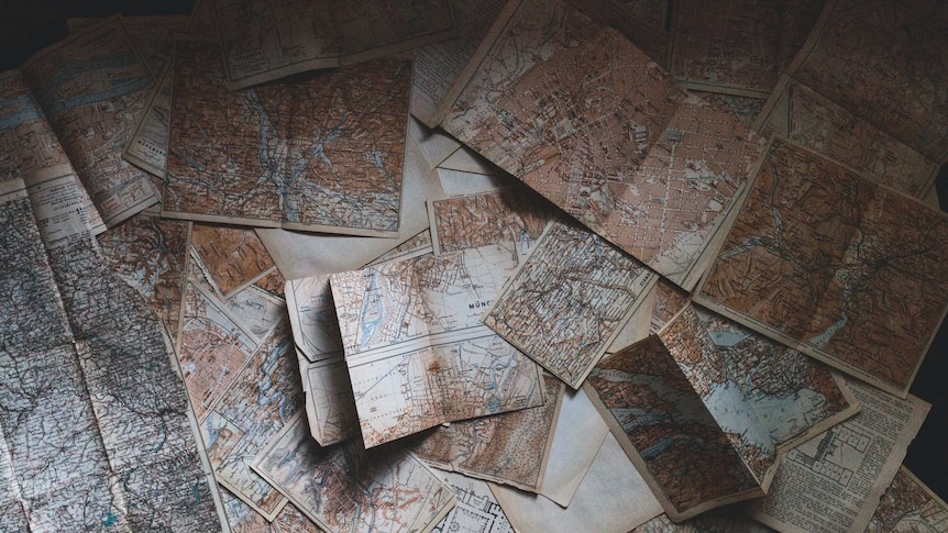 A collection of ornate old maps piled on top of each other.